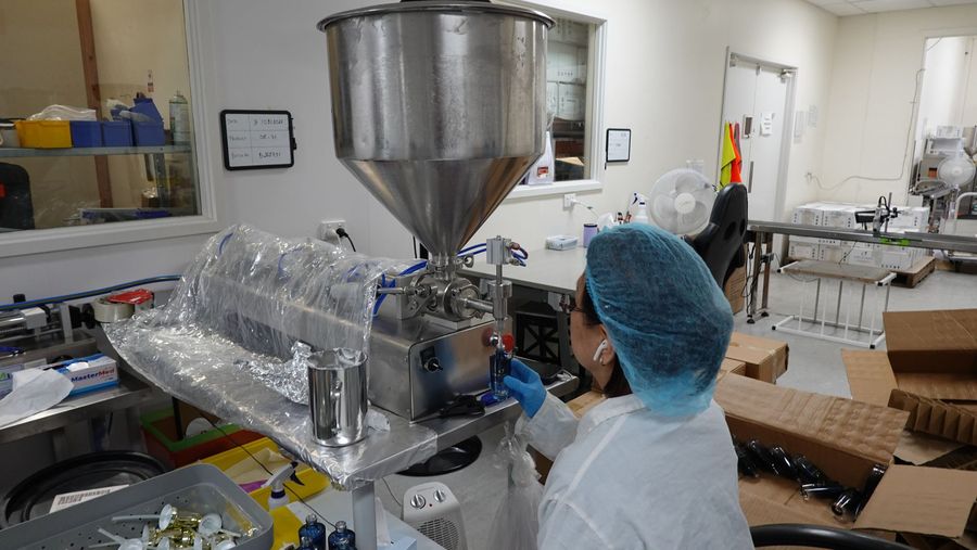 Operator in a hairnet at the piston filling machine