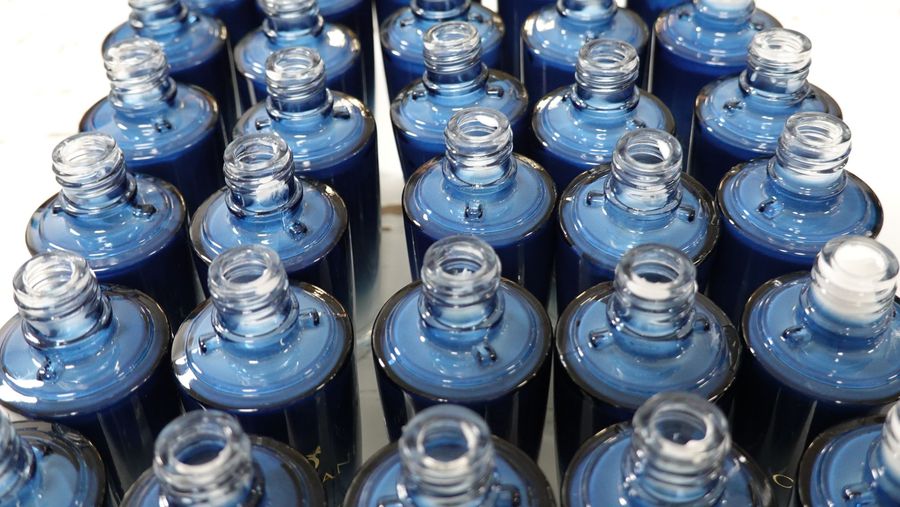 Overhead view of rows of empty blue gradient glass serum bottles