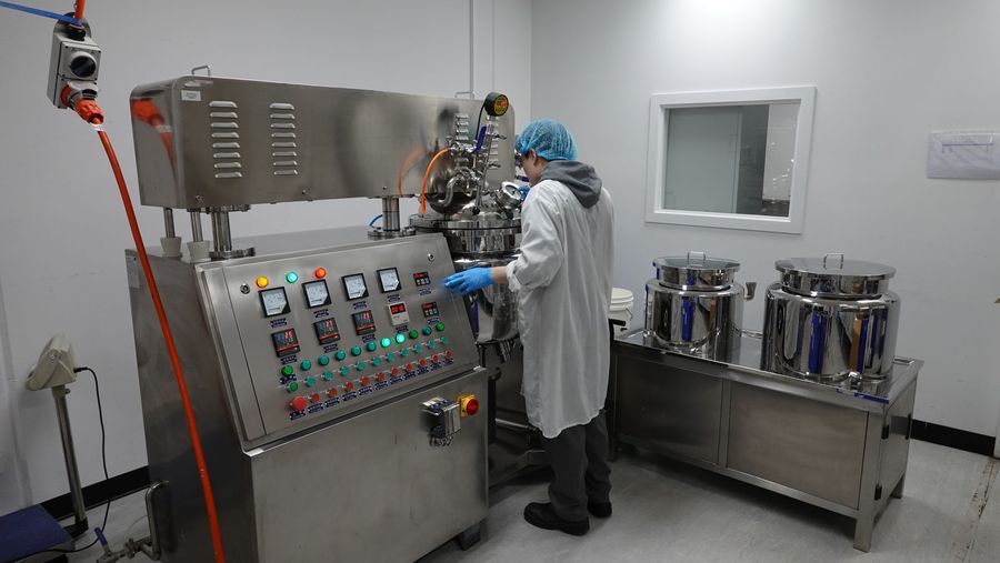 Operator at the emulsifier control panel in a clean production room