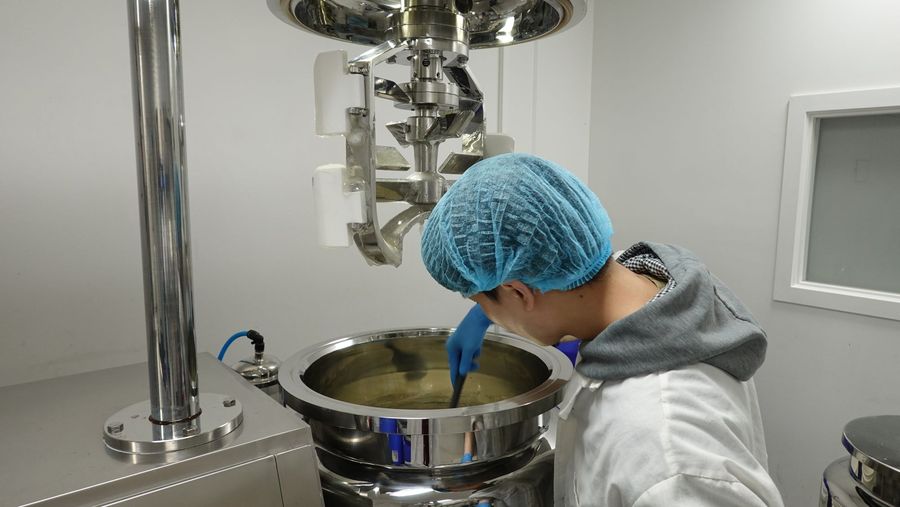 Operator in a hairnet checking cream inside the mixing vessel
