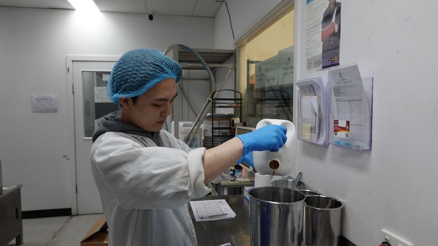 Operator measuring an ingredient with certificates on the wall behind